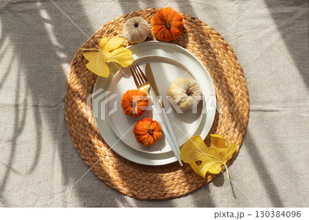 Autumn Table Setting with Decorative Pumpkins and Seasonal Leaves 130384096