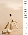 Eco bamboo toothbrush with black bristles balanced on natural wood decor 130384456