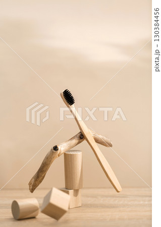 Eco bamboo toothbrush with black bristles balanced on natural wood decor Eco bamboo toothbrush with black bristles balanced on natural wood decor 130384456
