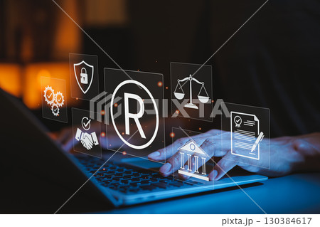 Registered Trademark and Intellectual Property Protection Concept. Typing on laptop with trademark symbol and legal icons, intellectual property, legal rights, brand protection, and business security. 130384617