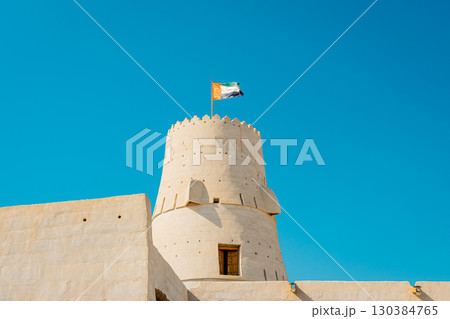 Stone arabic watchtower with waving United Arab Emirates National Flag in Al Jazirah Al Hamra haunted town in Ras Al Khaimah. High quality photo Stone arabic watchtower with waving United Arab Emirates National Flag in Al Jazirah Al Hamra haunted town in Ras Al Khaimah. High quality photo 130384765