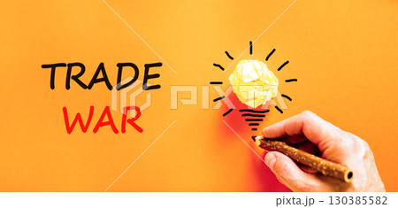 Trade war symbol. Concept word Trade war on beautiful orange paper. Businessman's hand. Light bulb icon. Beautiful orange paper background. Business trade war concept. Copy space. Trade war symbol. Concept word Trade war on beautiful orange paper. Businessman's hand. Light bulb icon. Beautiful orange paper background. Business trade war concept. Copy space. 130385582