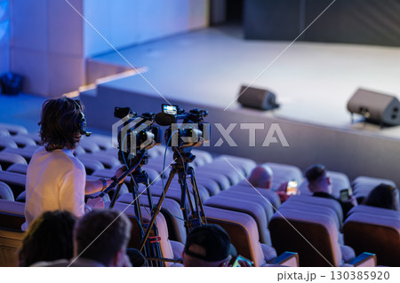 Videographer operating cameras during a live stage event with an audience Videographer operating cameras during a live stage event with an audience 130385920