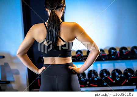 ジムで運動するかっこいい女性の後ろ姿　背中　仁王立ち　筋トレ女子 130386108