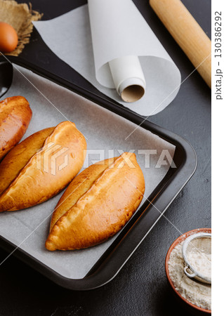 Freshly baked pies in baking tray, traditional homemade pastry with golden crust. Ukrainian piroshki Freshly baked pies in baking tray, traditional homemade pastry with golden crust. Ukrainian piroshki 130386292