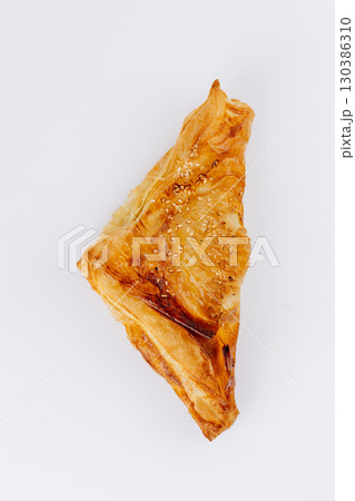 Golden puff pastry triangles with sesame seeds isolated on white background 130386310