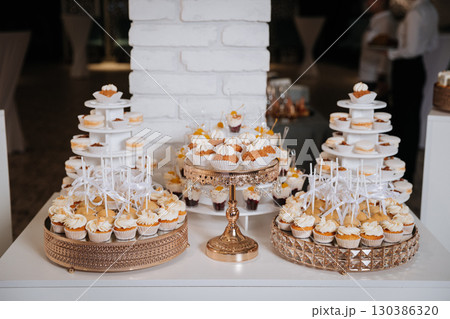 Elegant dessert table with cupcakes and sweets at a luxury celebration event Elegant dessert table with cupcakes and sweets at a luxury celebration event 130386320