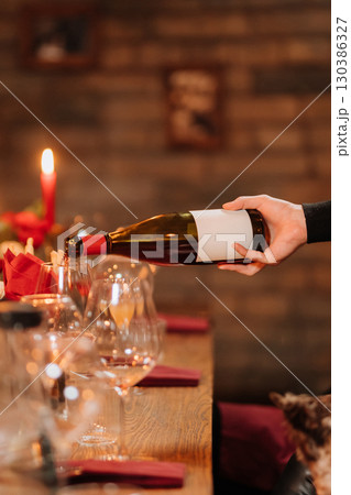 Pouring rose wine into glass at festive dinner with flowers and candlelight ambiance 130386327