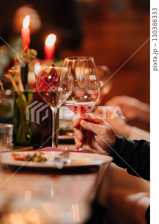 Elegant dinner moment with wine glass held during candlelit celebration or gourmet event Elegant dinner moment with wine glass held during candlelit celebration or gourmet event 130386333