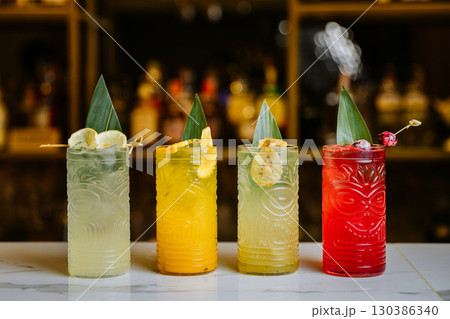 Colorful tiki cocktails with tropical garnishes on bar counter, vibrant and refreshing 130386340