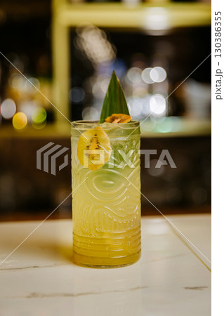 Tropical kiwi cocktail in tiki glass with garnish at bar counter, vibrant and refreshing 130386355