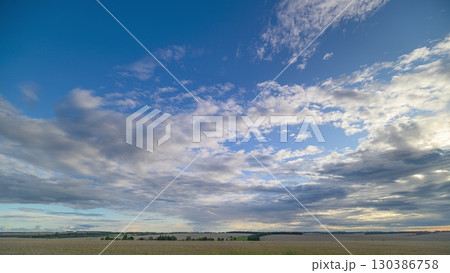 A scenic cloudy sky stretches over lush rolling fields, showcasing natures grandeur 130386758