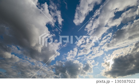 A Dynamic Sky Showcasing Fluffy Clouds Gracefully Set Against a Stunning Blue Horizon 130387022