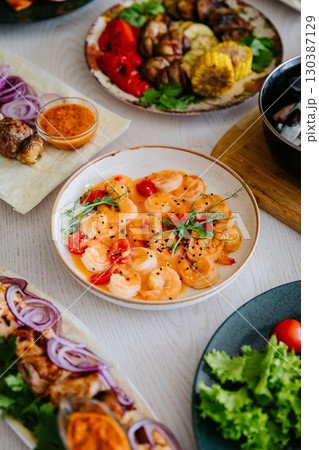 Shrimp in creamy spicy sauce with cherry tomatoes and herbs in ceramic bowl 130387129