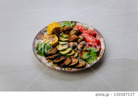 Grilled vegetables with herbs on ceramic plate. Colorful healthy vegan meal top view 130387137