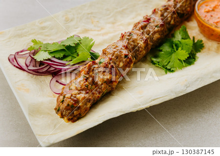 Grilled lamb lula kebab with onion, herbs, and spicy sauce on lavash bread Grilled lamb lula kebab with onion, herbs, and spicy sauce on lavash bread 130387145