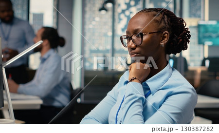 Trader frowning while looking at investment portfolio candlestick charts after unexpected market crash. African american woman upset by stock exchange account losses 130387282