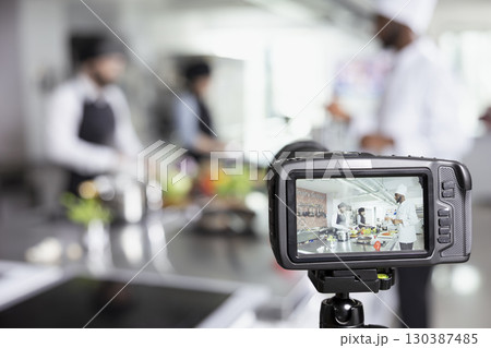 Culinary professionals recording a cooking school tutorial on camera, demonstrating food prep and plating techniques for an internet audience. Hosting a video training master class. 130387485