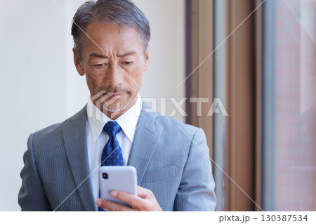 スマホを使うシニアビジネスマン スマホを使うシニアビジネスマン 130387534