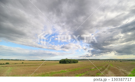 A Vast and Expansive Landscape Featuring Dramatic Clouds Above a Lush Green Field A Vast and Expansive Landscape Featuring Dramatic Clouds Above a Lush Green Field 130387717