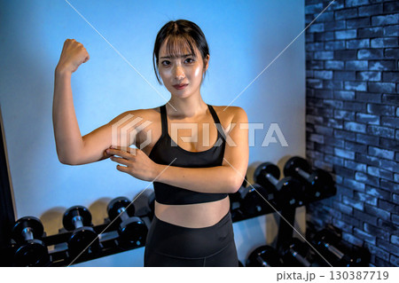 二の腕を触る女性　ジムで運動するかっこいい女性　力こぶ　上半身　筋トレ女子 130387719