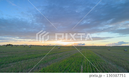 A Beautiful Serene Sunset Over Vast Lush Green Fields in a Picturesque Rural Landscape 130387751