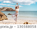 Young woman practicing Tree Pose yoga on beach by 130388058