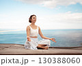 Woman practicing Lotus Pose on wooden platform 130388060