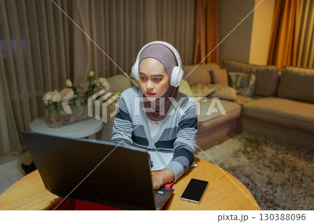 A Focused Young Woman Diligently Working on Her Laptop in a Cozy Living Room Space A Focused Young Woman Diligently Working on Her Laptop in a Cozy Living Room Space 130388096