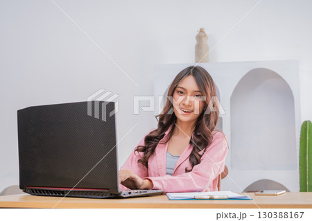 A Young Professional is Working on a Laptop in a Modern Home Office Environment A Young Professional is Working on a Laptop in a Modern Home Office Environment 130388167