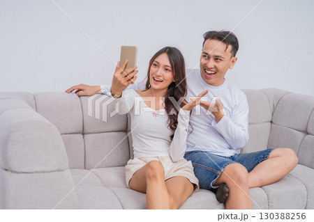 A Happy Couple Taking a Fun Selfie on a Cozy Couch Delightful Moments Captured 130388256