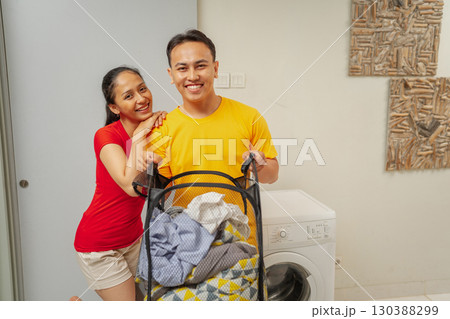 A Joyful Couple Enjoying Household Chores Together in Their Bright Laundry Room 130388299