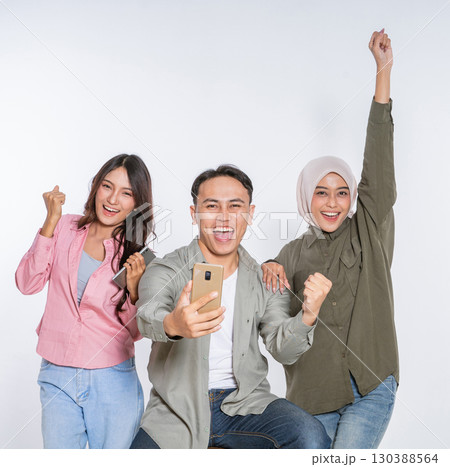 Joyful Friends Celebrating Together with Smartphone in Minimalist Setting 130388564