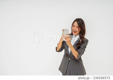 Excited Businesswoman Celebrating Success on Smartphone in Professional Attire 130388573