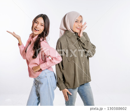 Stylish Women Posing Together in Trendy Outfits Against a White Background 130388602