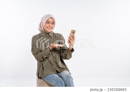 A Cheerful Young Woman Using a Smartphone While Dressed in a Casual Outfit 130388665