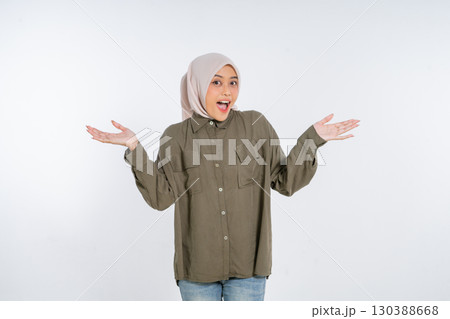 A Joyful Young Woman Dressed in a Hijab Expressing Surprise with Her Open Hands 130388668