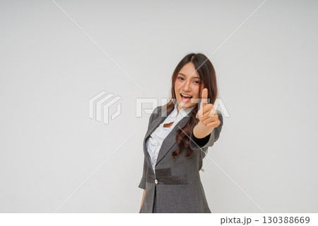 A successful businesswoman is proudly giving a thumbs up in professional attire 130388669
