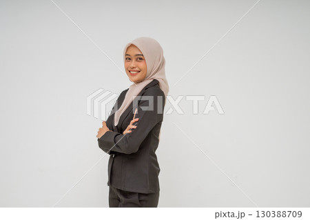 A confident young businesswoman dressed in professional attire, proudly wearing a hijab 130388709