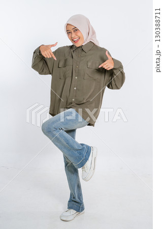 A Young Woman Dressed in a Casual Yet Stylish Outfit is Playfully Posing for a Photo Shoot 130388711