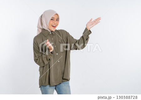 A cheerful young woman in a stylish hijab poses for the camera, smiling brightly A cheerful young woman in a stylish hijab poses for the camera, smiling brightly 130388728