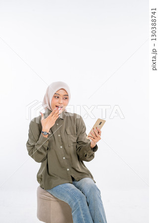 An Excited Young Woman Happily Checking Her Phone with a Surprised Expression An Excited Young Woman Happily Checking Her Phone with a Surprised Expression 130388741