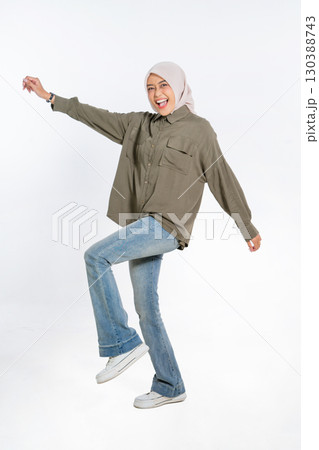 A Joyful Young Woman Expresses Her Happiness While Dancing in Casual Attire with a Hijab A Joyful Young Woman Expresses Her Happiness While Dancing in Casual Attire with a Hijab 130388743