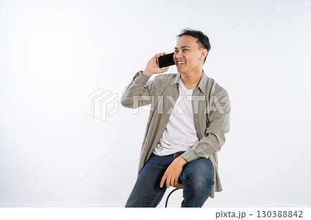 A Young Man with a Smile Engaged in Conversation on His Smartphone in a Studio 130388842