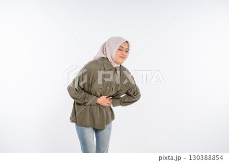 A young woman wearing a hijab is currently experiencing some stomach discomfort 130388854