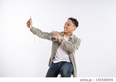 A Young Man Capturing a Selfie While Wearing a Happy and Joyful Expression A Young Man Capturing a Selfie While Wearing a Happy and Joyful Expression 130388856