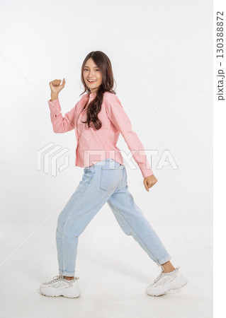 A joyful young woman dances gracefully in her casual outfit on a white background A joyful young woman dances gracefully in her casual outfit on a white background 130388872