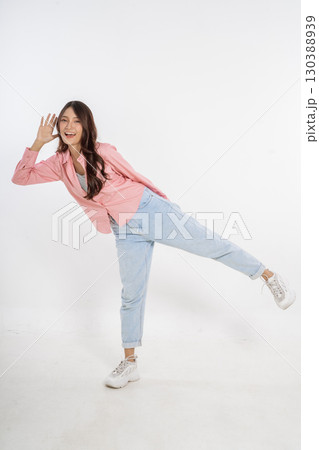 A Stylish Young Woman Wearing a Pink Blazer is Posing Playfully in her Casual Outfit 130388939