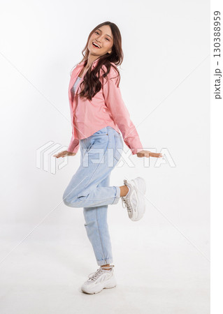 Joyful Young Woman in Casual Outfit Posing Playfully Against White Background Joyful Young Woman in Casual Outfit Posing Playfully Against White Background 130388959