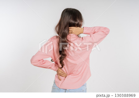 A Young Woman with Long Hair Holding Her Back While Dressed in Comfortable Attire 130388969